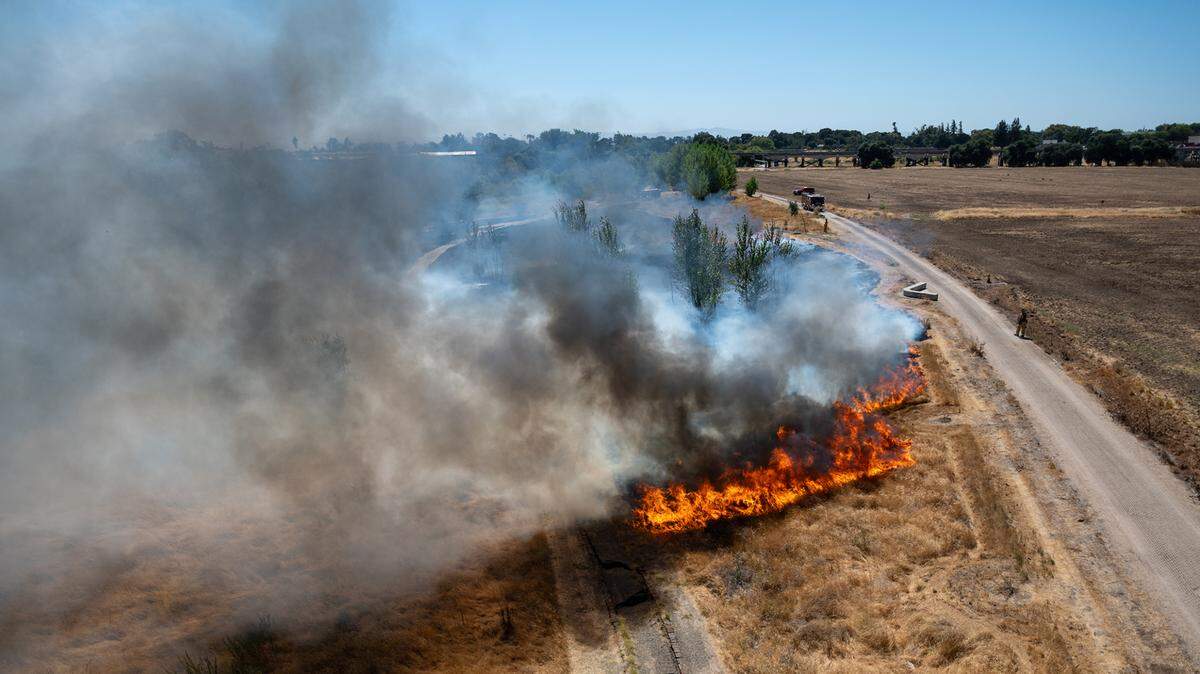 Modesto Fire contains a fire at the Tuolumne River Regional Park seen from the 9th Street Bridge in Modesto, Calif., on Friday, Aug. 4, 2021.
