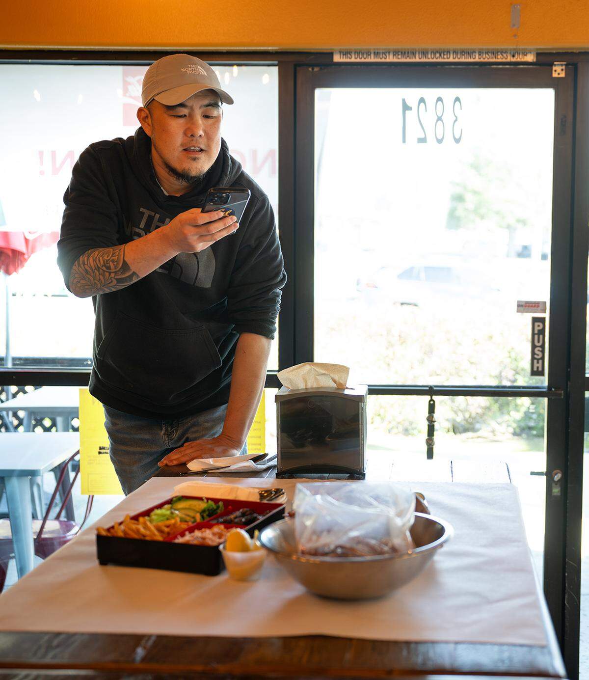 Co-owner Jack Wu photographs some of the menu items for social media at Cajun Bento restaurant in Turlock, Wednesday, Jan. 29, 2025.