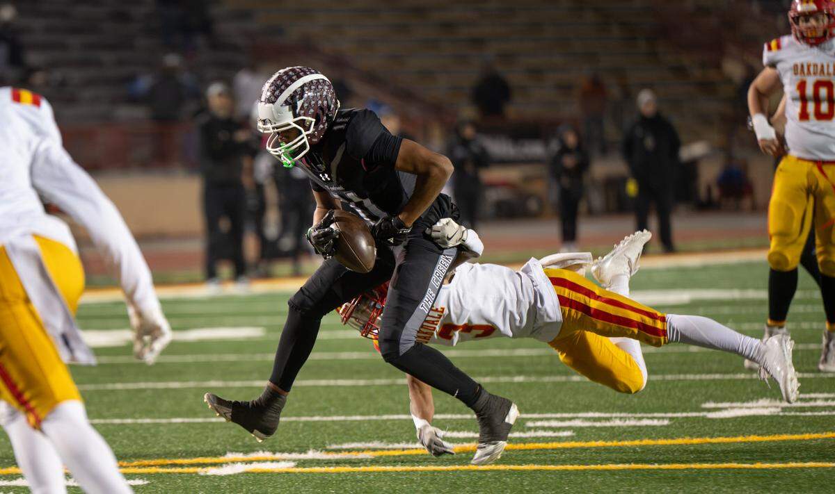 Woodcreek receiver Jack Torrey hangs onto the ball as Oakdale’s Beau Kesterson attempts the tackle during the CIF Sac-Joaquin Section Division III championship football game at Hughes Stadium in Sacramento on Friday.
