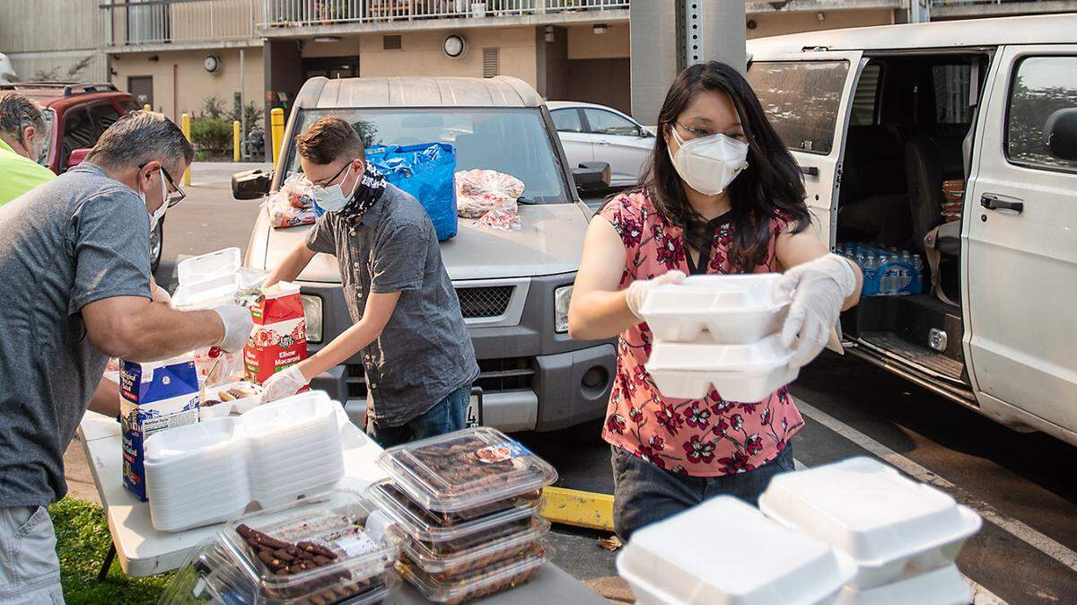 Volunteers Cheyene Hajjar, right, William Nickell, middle, and Mike Freese, left, pack BBQ lunch for residents of Ralston Tower druing Love Modesto in Modesto, Calif., on Saturday, Oct. 3 2020.