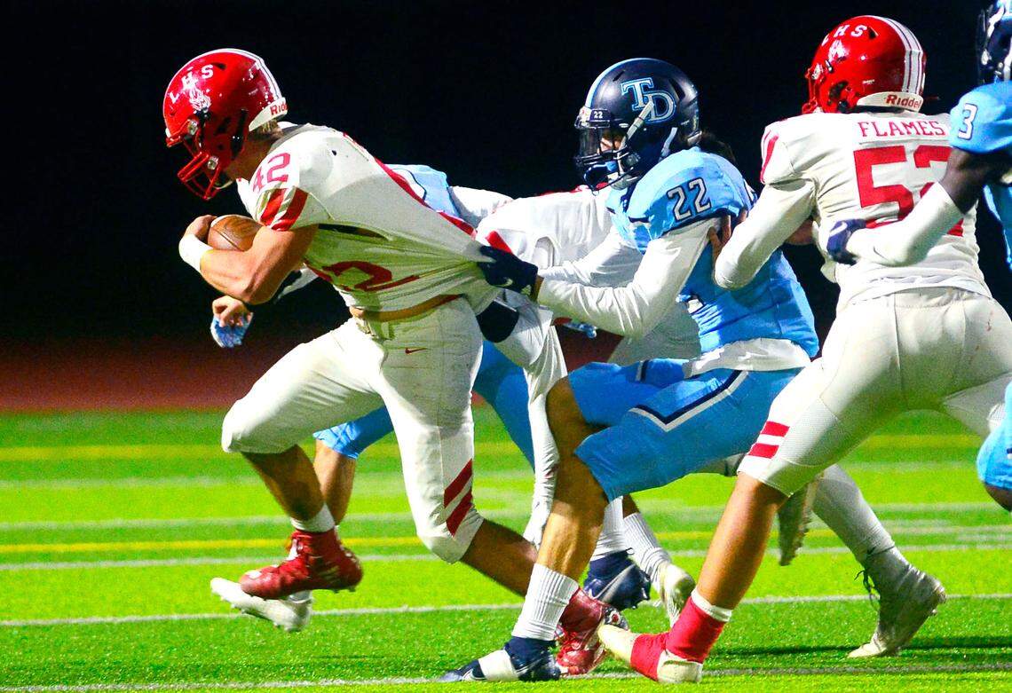 Downey’s David Jones (22) holds back Lodi running back Caleb Duncan (45) during a CIF Sac-Joaquin Division II playoff game between Downey and Lodi high schools at Downey High in Modesto, California, on Nov. 5, 2021.