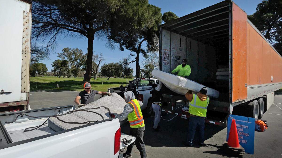 Workers from Bye Bye Mattress collect mattresses during Modesto’s “drive up, drop off” refuse collection event at John Thurman Field in Modesto, Calif., Saturday, March 25, 2023.