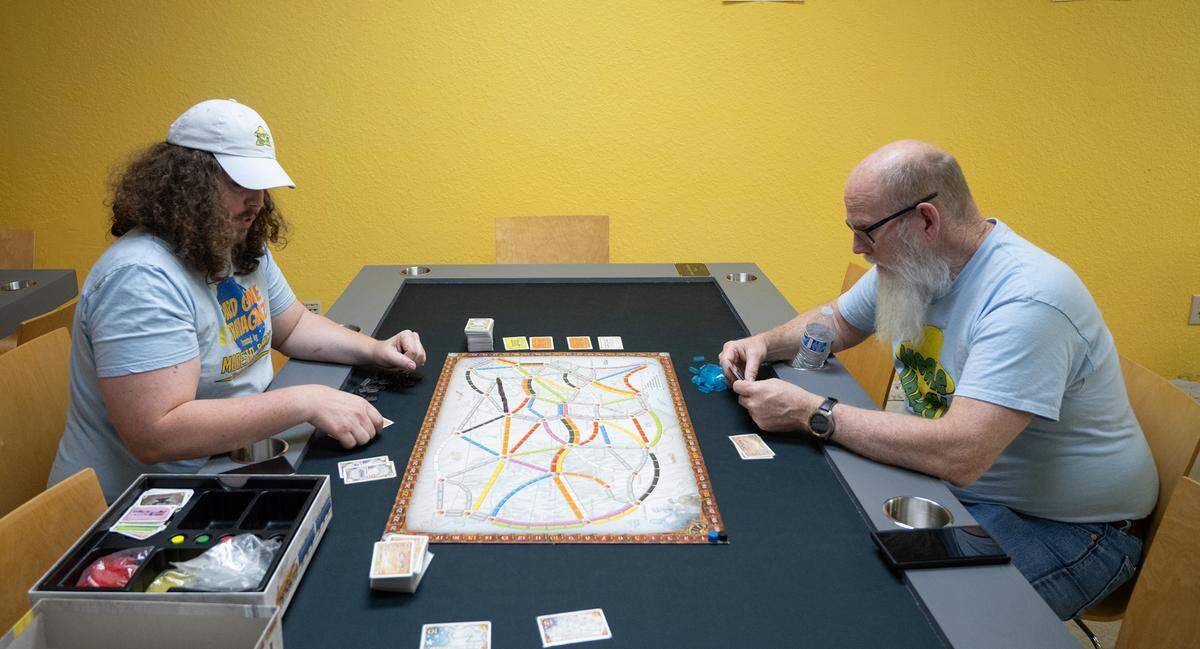 Rob Van Tuinen, left, and his father Bob Van Tuinen demonstrate the game Ticket to Ride on one of the gaming tables at Meeple Valley Board Game Cafe in Modesto, Calif., Thursday, March 21, 2024.