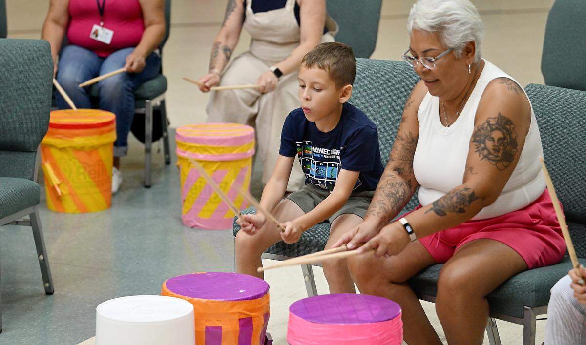 Hope Duffy and her grandson Levi Esquivel, 8, hit drums during a drumming workshop for grieving families of Jessica’s House in Turlock, Calif., Thursday, July 18 , 2024. Josh Robinson, a Philadelphia-based percussionist, uses drumming as a tool for coping with grief.