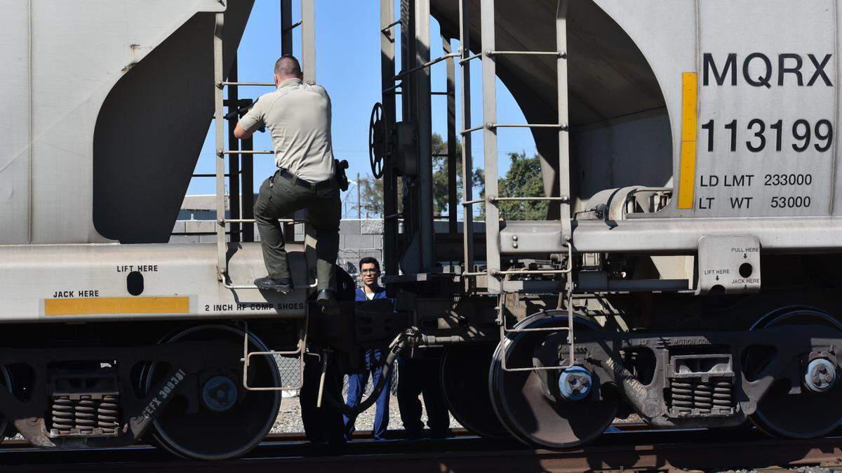 A deputy with the Stanislaus County Coroner’s Office climbs between cars of a train stopped at Carver Road and North Ninth Street in Modesto on Wednesday morning, July 21, 2021. The body of a woman struck by the train was on the other side.