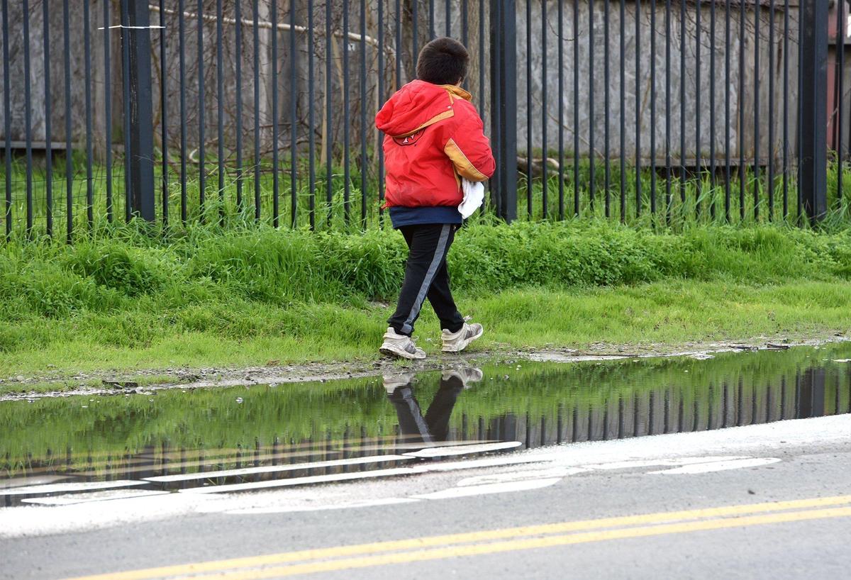 A child walks around a puddle in an area with no sidewalks on Tenaya drive Tuesday afternoon February 5, 2019 in the Airport neighborhood in Modesto, Calif. Last week the Stanislaus Council of Government (StanCOG) approved the acceptance of a $4.9 million grant from the Active Transportation Program (ATP), a State funded program primarily for bicycle and pedestrian safety projects in the S Modesto Airport Neighborhood.