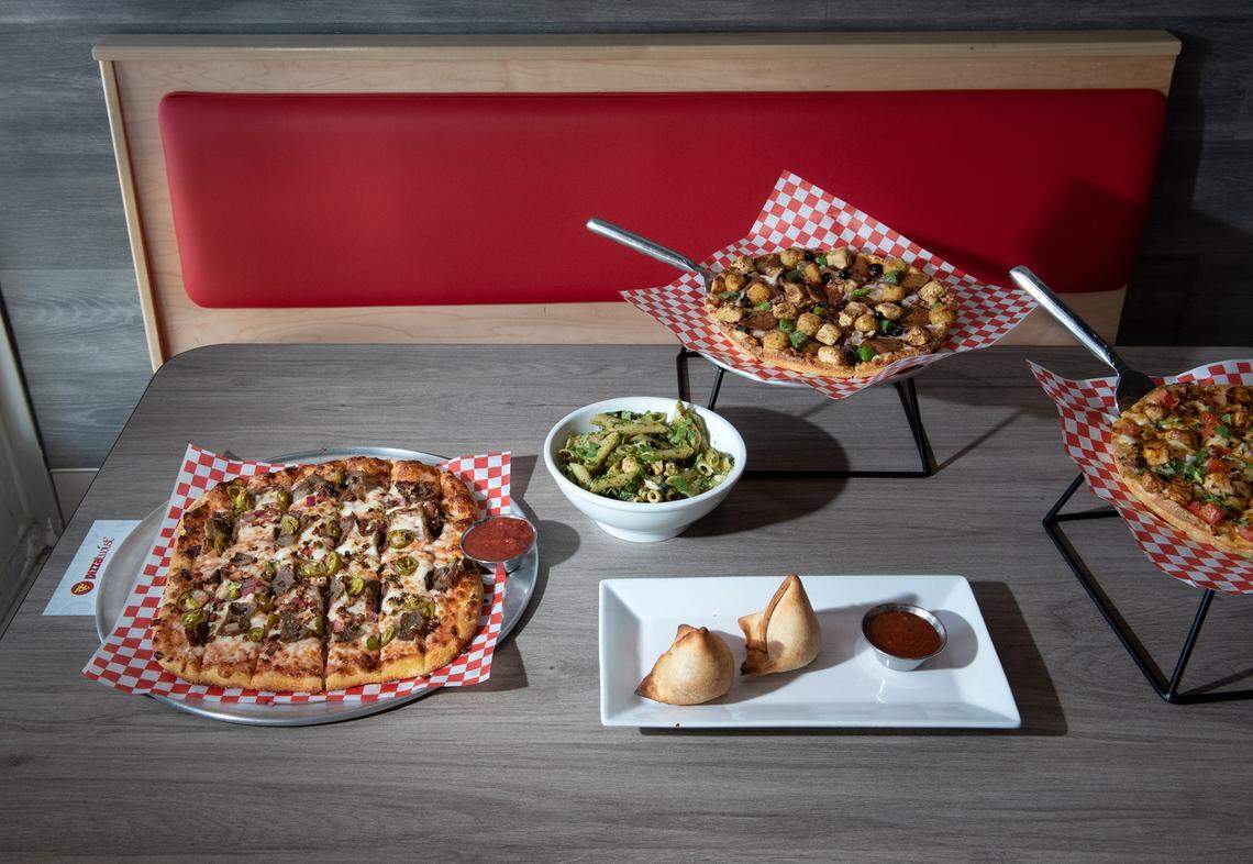 From the left, spicy lamb breadsticks, palak paneer pasta twist, samosas, vegan combination pizza and butter pizza at Pizza Twist in Modesto, Calif., Thursday, April 6, 2023.