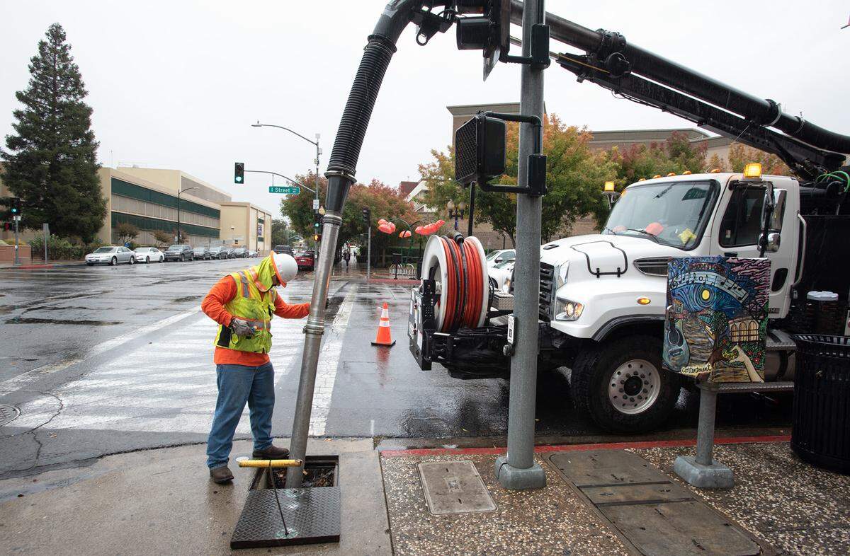 A city utilities worker clears a storm drain on I Street in Modesto, Calif., Tuesday, Nov. 1, 2022.
