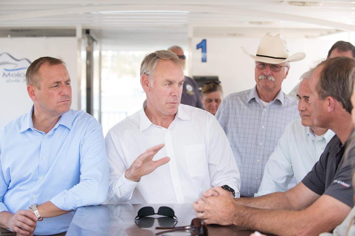 Interior Secretary Ryan Zinke, middle, talks with marina owner Darin Mills, right, at New Melones Lake in Calif., Friday, July 20, 2018. Rep. Jeff Denham, is at left and congressman Tom McClintock is second right.