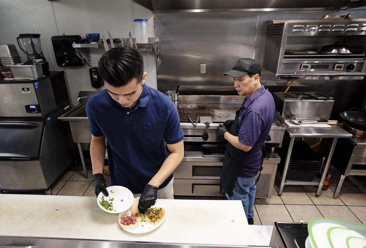 Nick Chan prepares poke tacos as his father Anthony watches at Terracota Pub in Turlock, Calif., Tuesday, Sept. 24, 2019.