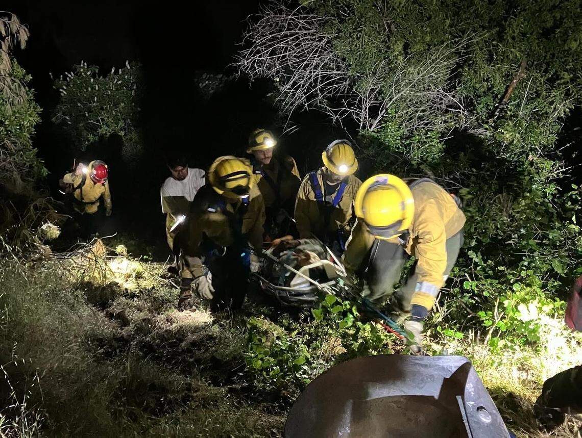 Firefighters use a rope rescue system to carry an injured patient up a steep hillside after a crash off New Priest Grade in Tuolumne County on April 19, 2026.