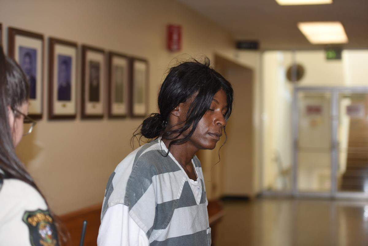 Wearing a gray striped jail uniform, Zella Latrice Holmes is escorted by a Stanislaus County sheriff’s deputy into court for her arraignment Tuesday, Sept. 30, 2025, in Modesto. Prosecutors allege Holmes fatally shot her longtime partner, Franklin Martin, inside a Howard Johnson Inn in Ceres.