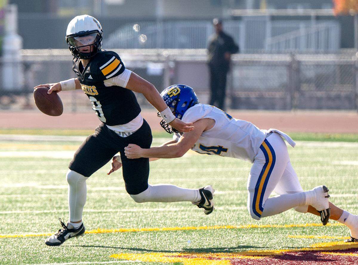 Hughson’s Robert McDaniel scrambles under pressure from a Sutter defender during the Sac-Joaquin Section Division 5 championship game at Sacramento City College in Sacramento, Saturday, Nov. 30, 2024.