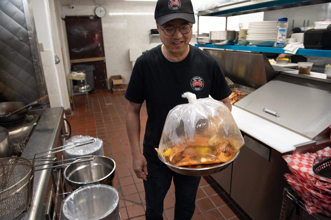 Owner Kevin Lin holds a seafood combo at Akitaca Crab seafood restaurant in Modesto, Calif., on Wednesday, March 16, 2022.