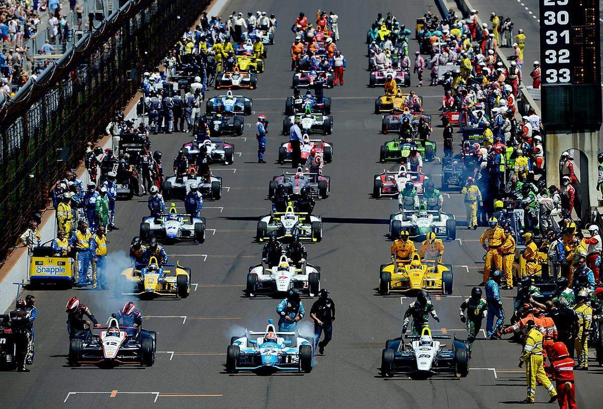 Will Power of Australia, driver of the #12 Verizon Team Penske Chevrolet Dallara; James Hinchcliffe, driver of the #27 Andretti Autosport Honda Dallara; and Ed Carpenter, driver of the #20 Fuzzy’s Vodka / Ed Carpenter Racing Chevrolet Dallara, lead the start the 98th running of the Indianapolis 500 at Indianapolis Motor Speedway on May 25, 2014.