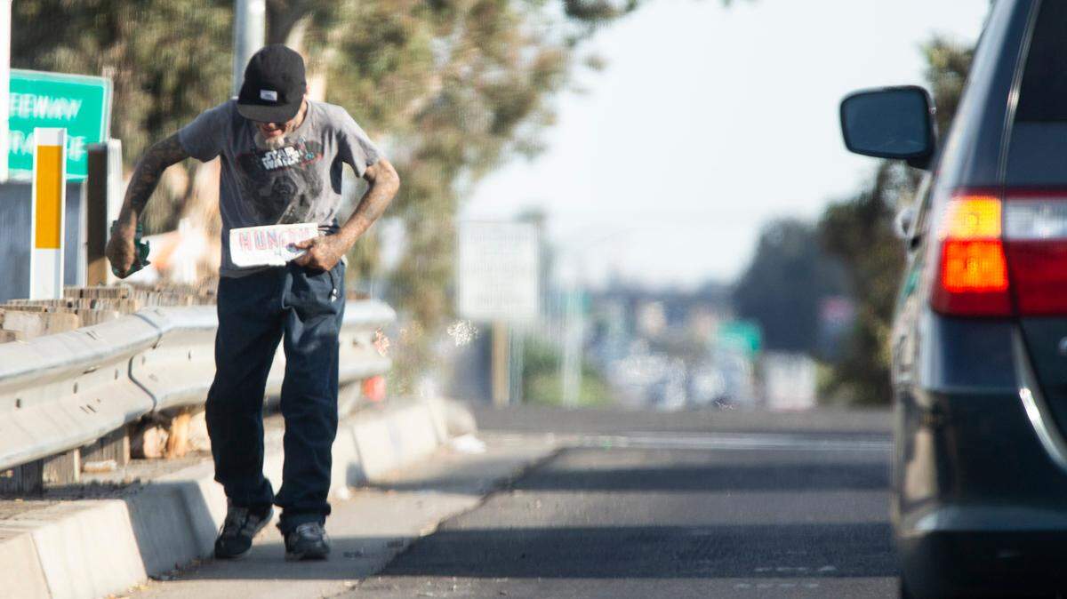 A man walks along a line of cars on an off ramp of southbound highway 99 at Hatch Road holding a sign stating “hungry” on Sunday, Sept. 22, 2019.