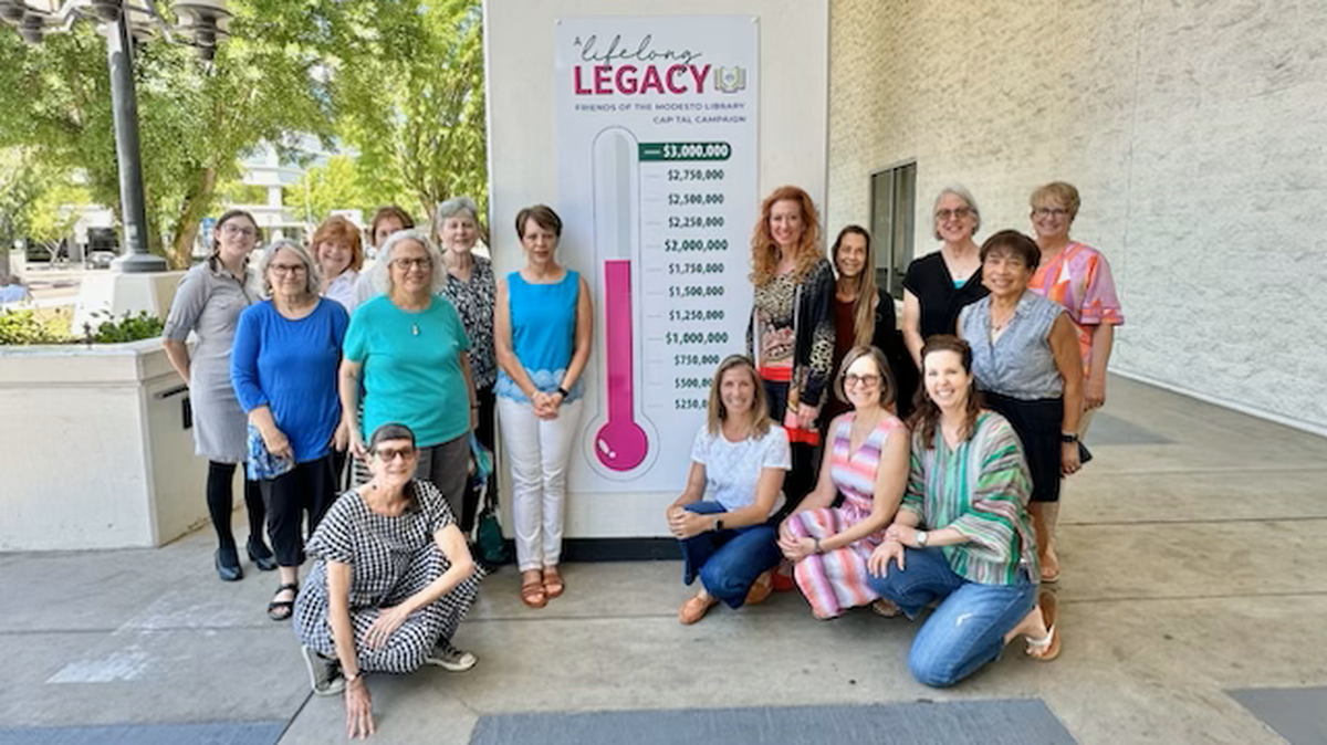  Friends of the Modesto Library gather around a fundraising thermometer outside the Modesto Library.