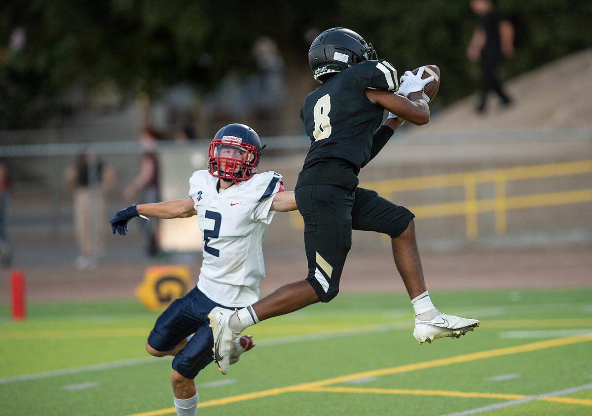 Enochs’s Marley Okoro makes a catch as Beyer’s Brock Gross defends during Friday’s game at Downey High School in Modesto, Calif., on August 19, 2022.
