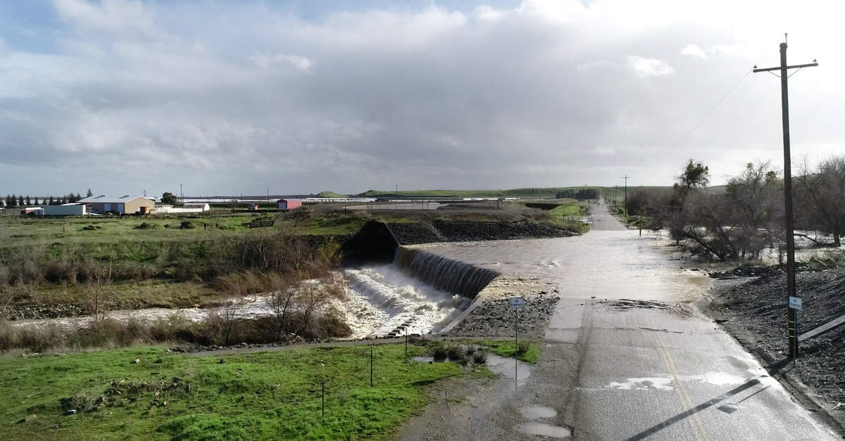 Water from Orestimba Creek flows over Bell Road in Newman, Calif., Tuesday, Jan. 10, 2023.