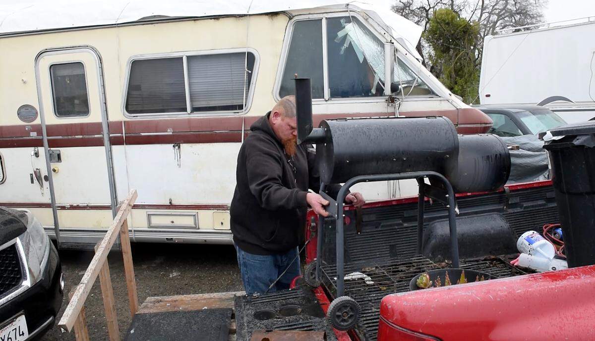 Catfish Camp RV park resident Eldon Brown unloads a grill after he and other residents moved to higher ground up to Crows Landing Road just above the park north of Newman, Calif., Wednesday, Jan. 11, 2023. The river is expected to crest the leeve behind the RV park.