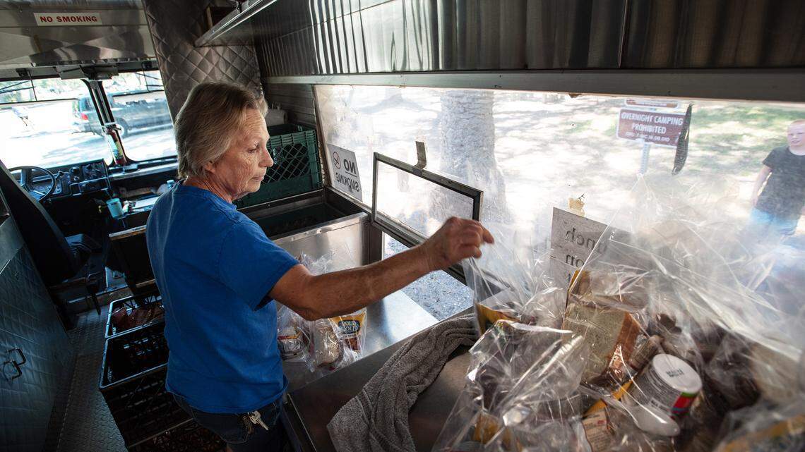 United Samaritans Foundation’s food truck supervisor Glenda Price hands out food during lunch at Mono Park in Modesto, Calif., on Friday, June, 24, 2022.