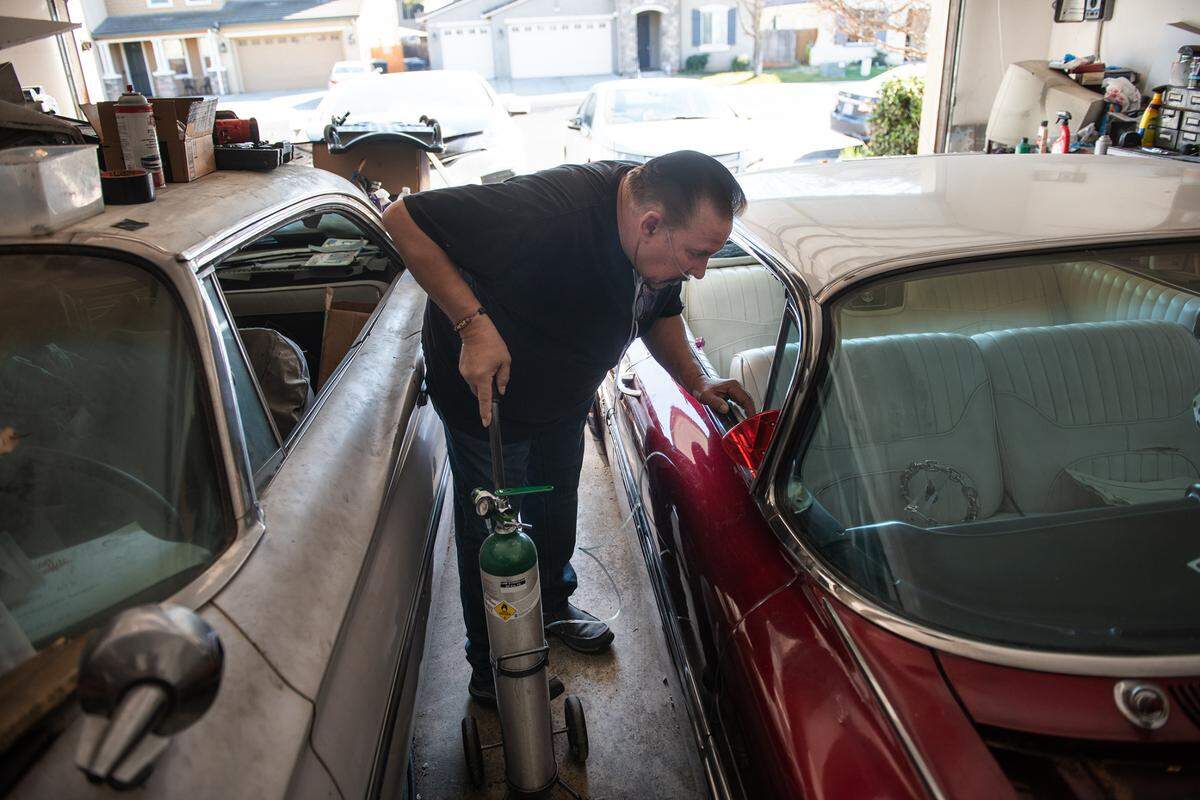 Mickey Davis looks at his classic Chevy 1959 Impala at his home in Modesto, Calif., on Friday, Feb. 25, 2022. Davis, 64, came down with COVID pneumonia and was hospitalized for 17 days, he said before COVID he was able to work on his cars but now has trouble remembering how to do simple fixes “I can’t even think straight sometimes”. Five months later, he still has breathing problems and uses oxygen at home.