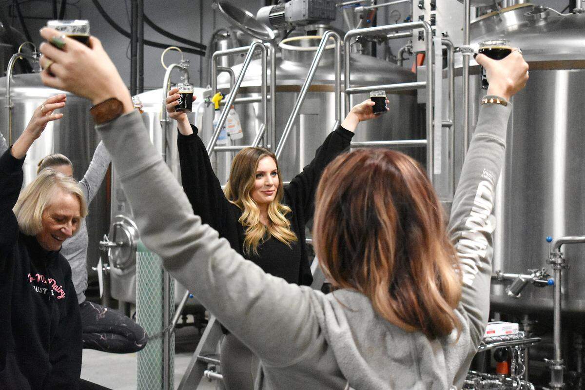 Jessica Egli, center, holds her beers high during a yoga and beer session at Blaker Brewing in Ceres on Sunday morning, Jan. 19, 2020.