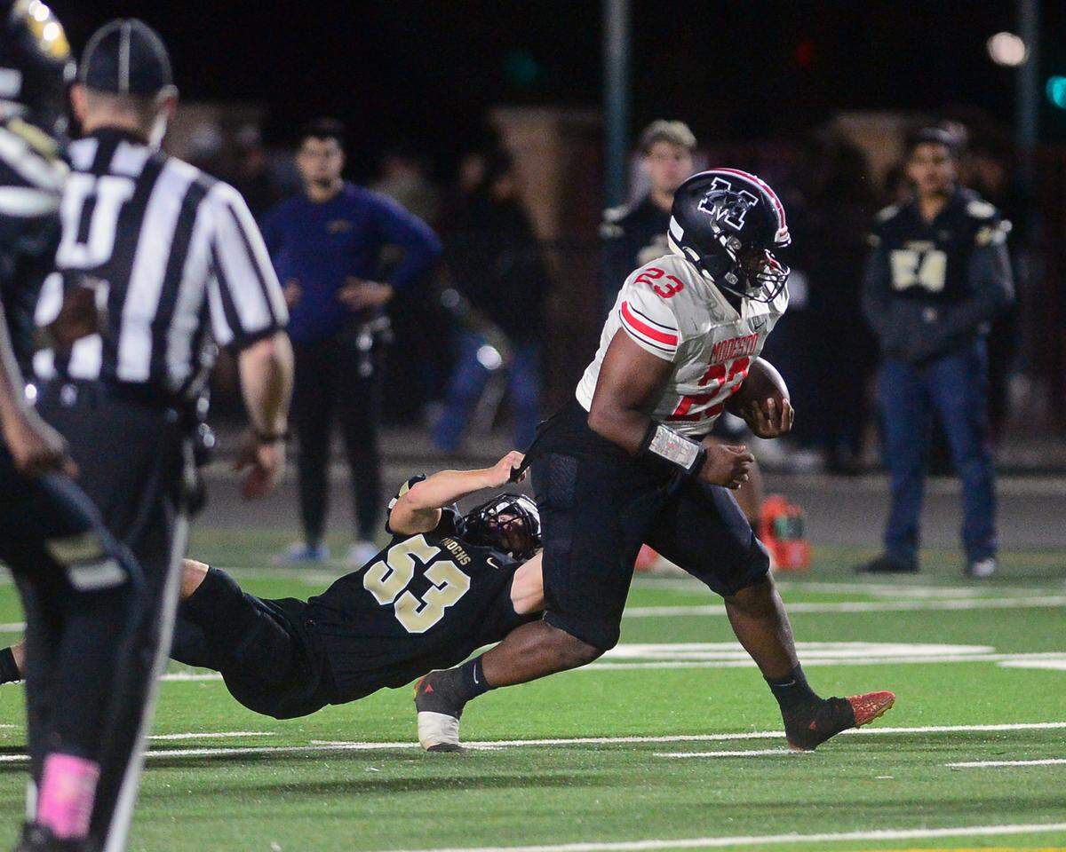 Modesto High running back Jalyn Woods drags a defender during a game against Enochs at Johansen High School in Modesto, Calif., on Oct. 28, 2022.