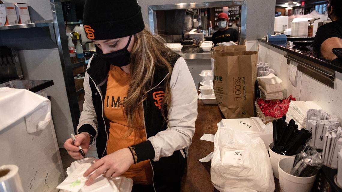 Sever Heather Braun prepares take-out orders at Kimoto Sake & Sushi in Modesto, Calif., on Saturday, Jan. 30, 2021.