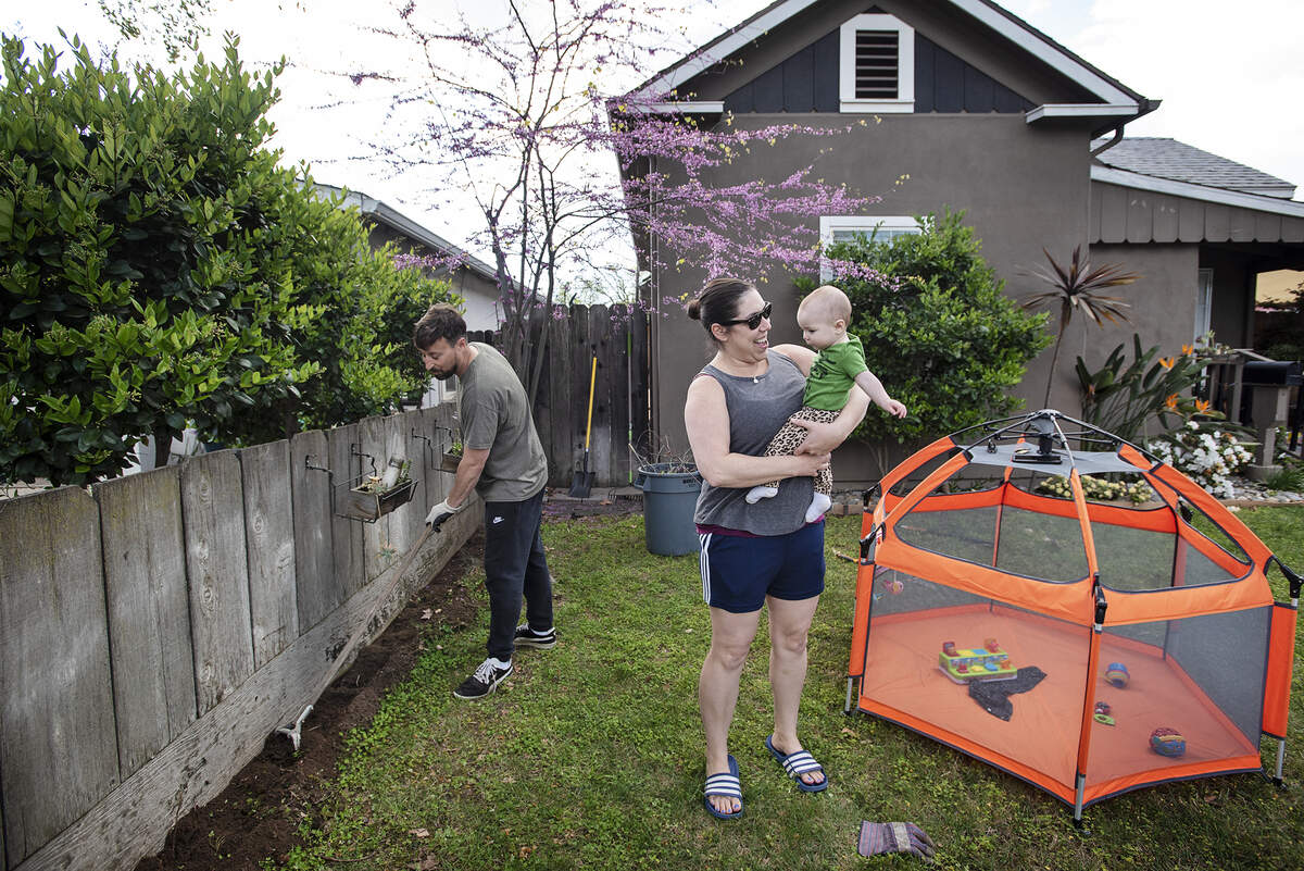 Modesto residents Stephen and Julie Brooks work in their front yard and watch their six-month-old daughter Mia in Modesto, Calif., on Friday, March 20, 2020. Both are public school teachers and have spent the “stay-at-home” period doing projects around the house.