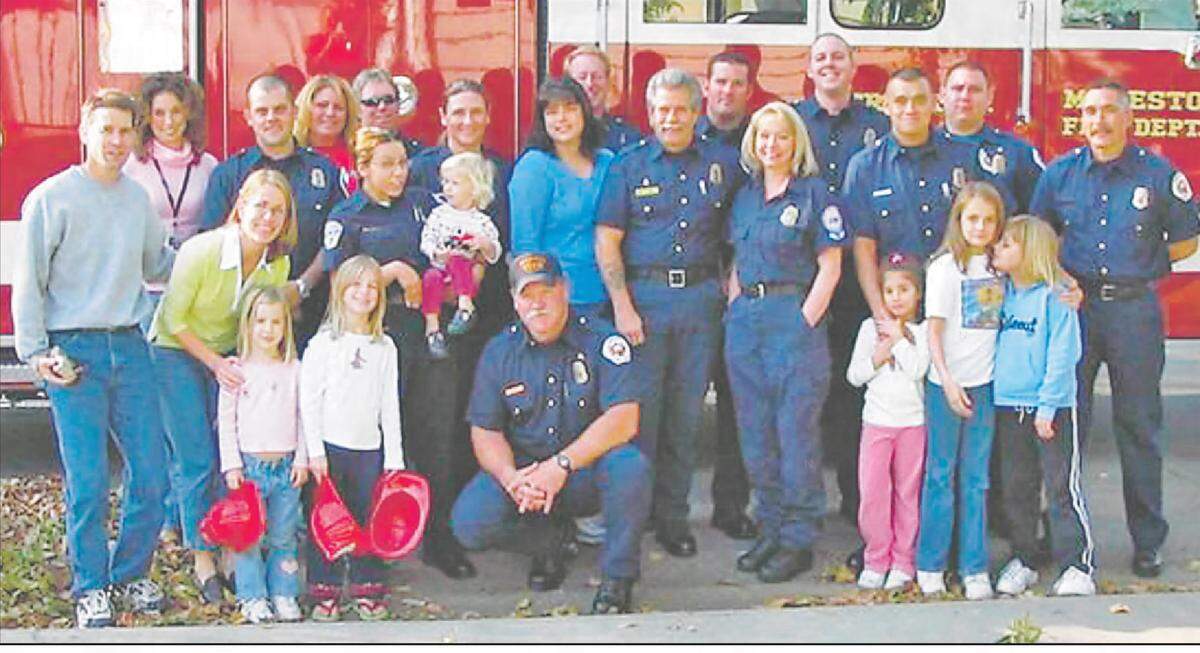 LeAnn Riley in 2008, pictured in the middle in blue, with emergency medical professionals and the family of then 21-month-old Laurel Gates. The child fell into a pond and was found unresponsive but survived thanks in part to Riley, who assisted the family with CPR until paramedics arrived. Laurel made a full recovery.