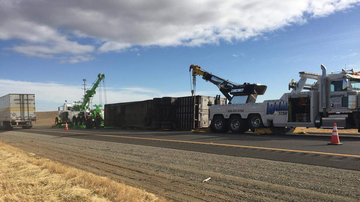 Tow truck crews work to remove a big-rig trailer from Interstate 5 in Patterson after it overturned and went down an embankment early Tuesday, May 12, 2020.