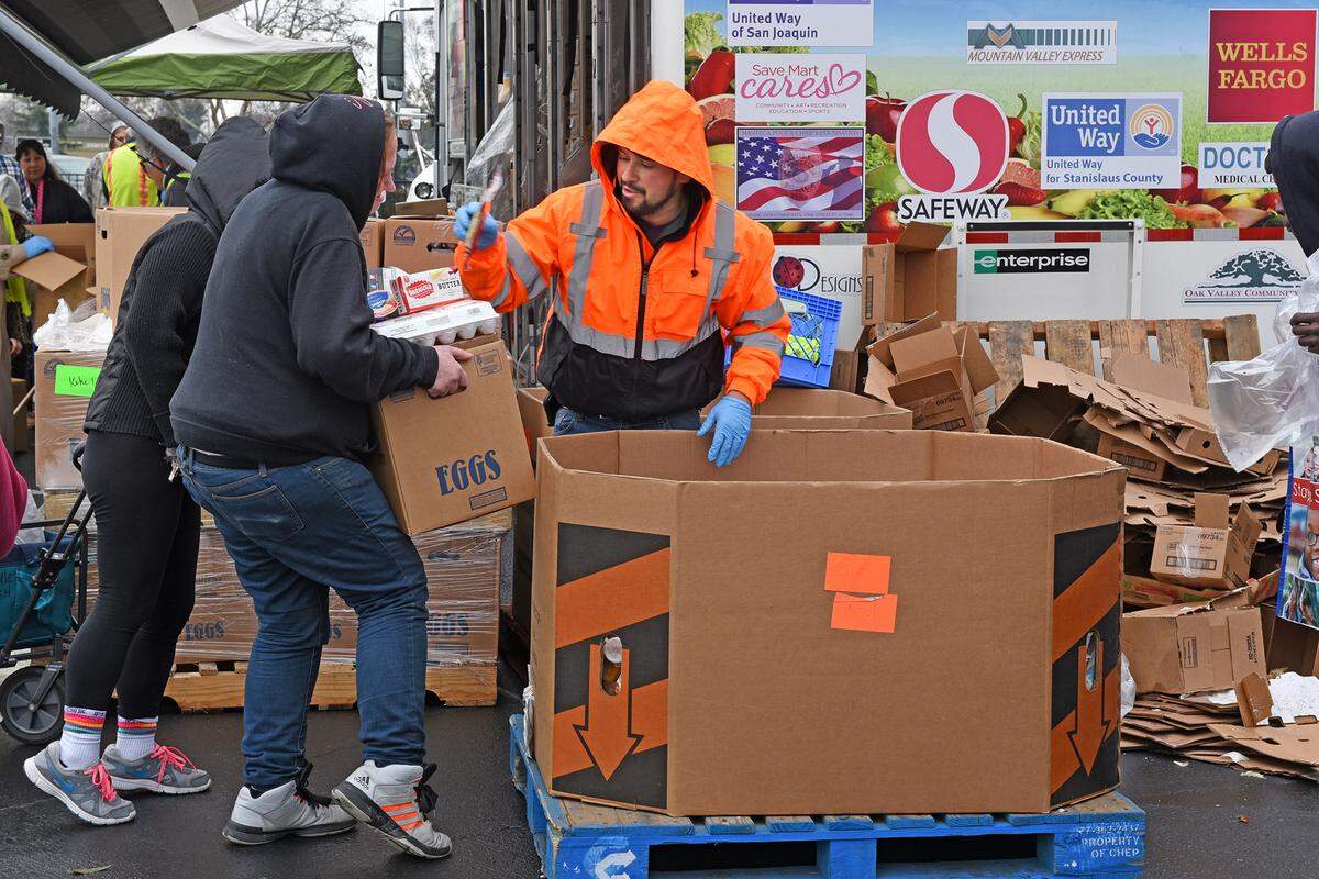 Cesar Rangel (center) fills boxes Monday morning January 22, 2018 at Pentecostal Church in downtown, Modesto, Calif. Second Harvest Food Bank has the food giveaway once a month in Modesto. The next one is scheduled for February 12th.