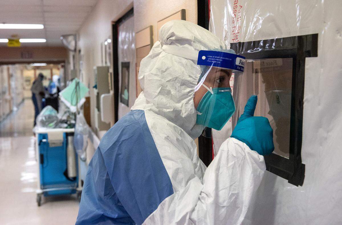 Nurse Summer Elmore checks on a patient through the door in the COVID unit at Central Valley Specialty Hospital in Modesto, Calif., on Tuesday August 18, 2020.