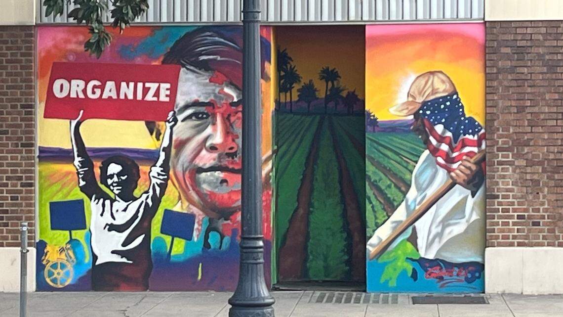 A mural shows and image of Cesar Chavez with Delores Huerta holding a sign that reads "Organize!" and a farm worker in a field 