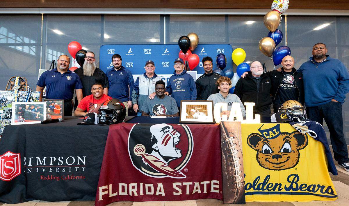 Central Catholic football players Anthony Todd, left, Manasse Itetem, middle, and Brooklyn Cheek, right, pose for pictures with their coaches during a National Signing Day ceremony at Central Catholic High School in Modesto, Calif., Wednesday, Dec. 20, 2023.