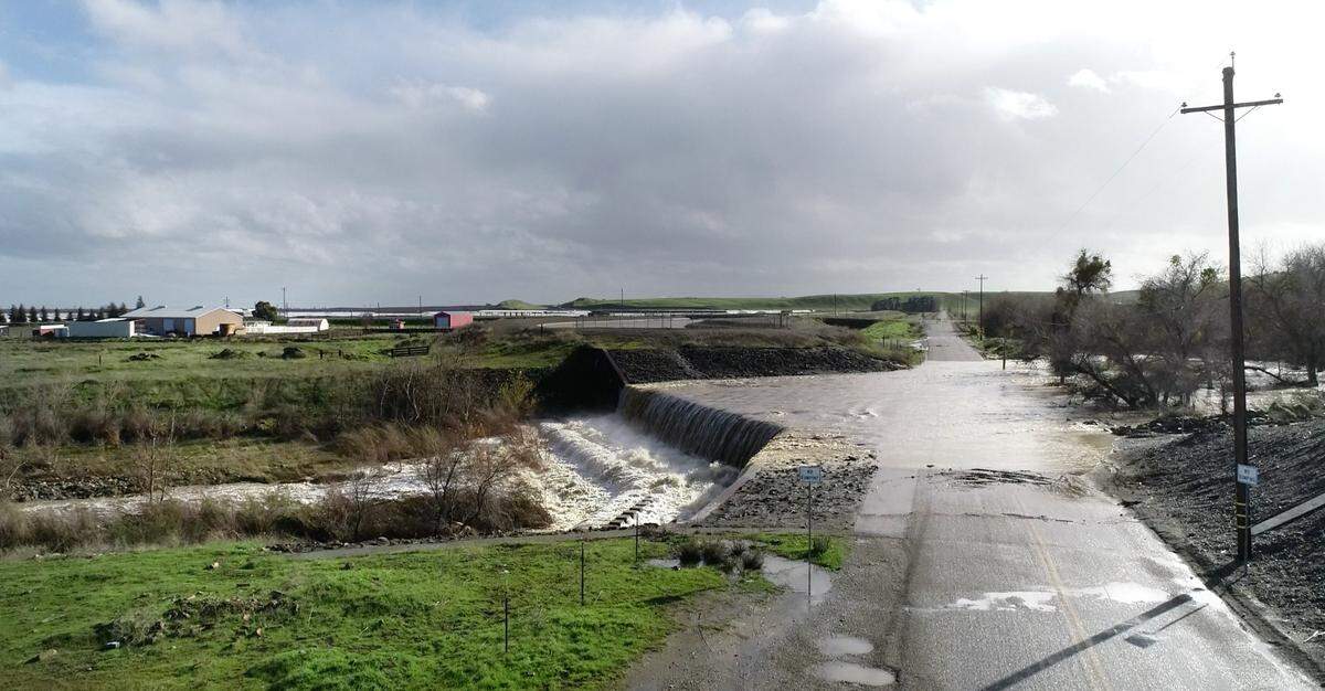 Water from Orestimba Creek flows over Bell Road in Newman, Calif., Tuesday, Jan. 10, 2023.