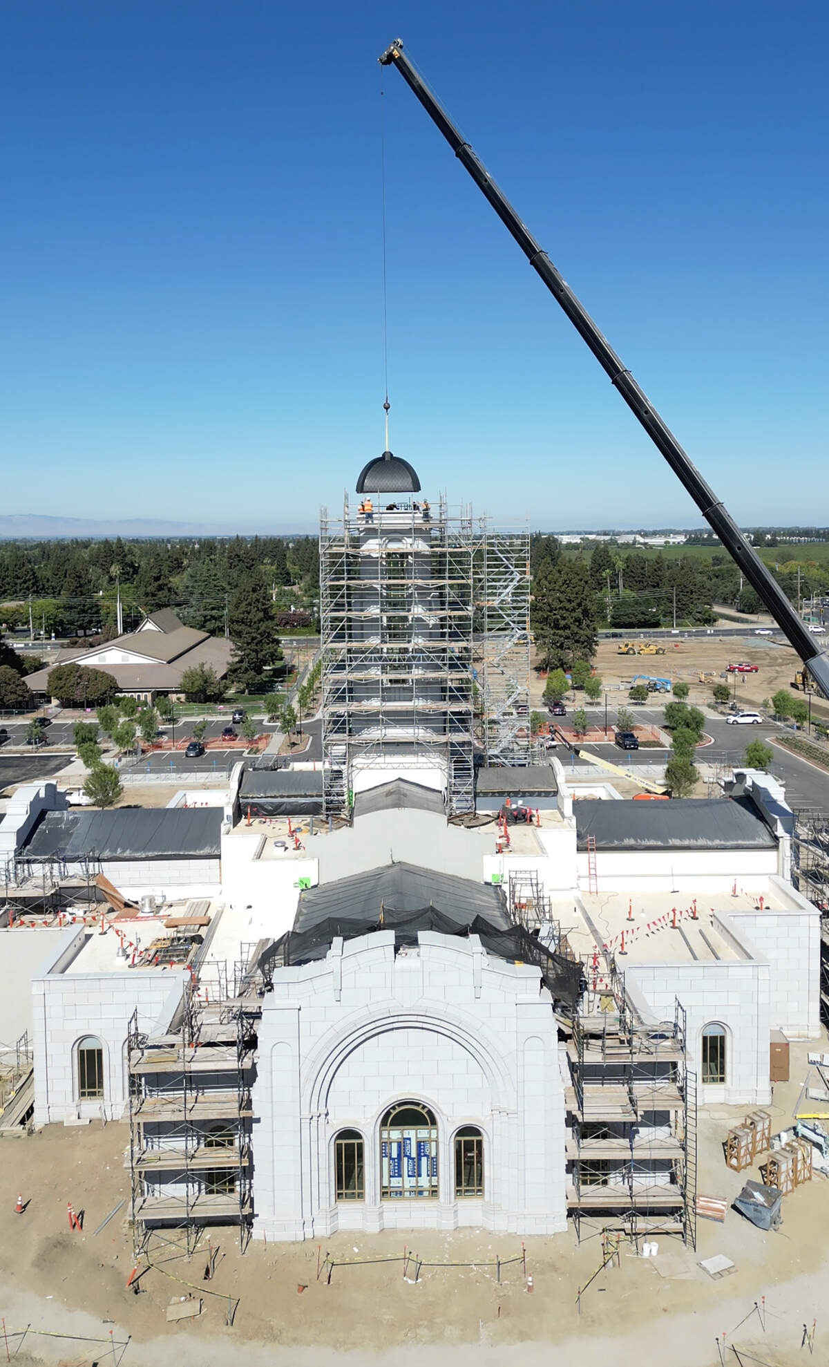 A crew places the capstone on the Modesto Temple of The Church of Jesus Christ of Latter-day Saints during construction in August 2025.