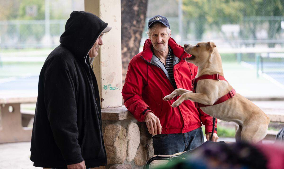 Homeless residents Gary McNeil, right, and Kevin Walker, left, with Walker’s dog Ally at Graceada Park in Modesto, Calif., Wednesday, March 29, 2023. 