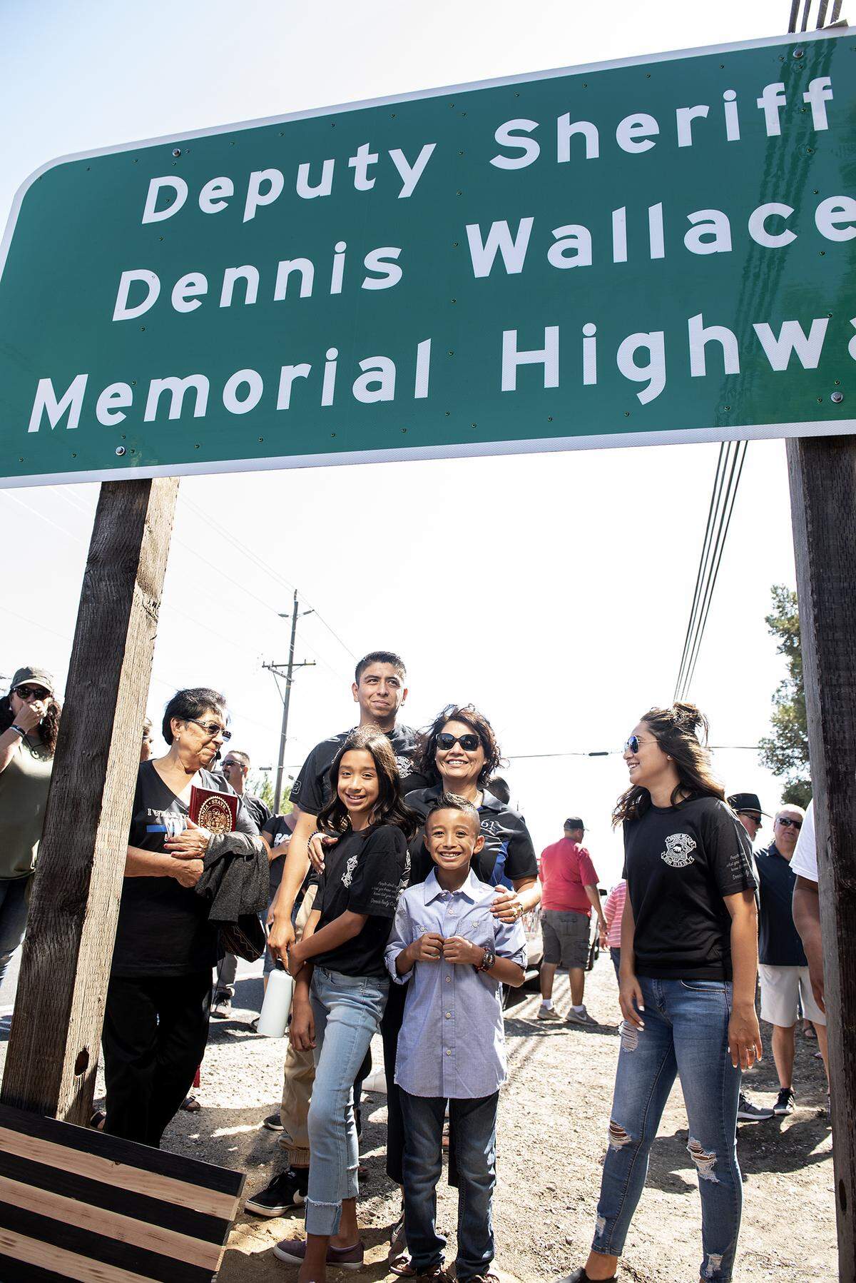 Mercedes Wallace, middle, is surrounded by members of her family as a section of Highway 132 is dedicated in honor of the her husband Dennis Wallace near Root Road east of Empire, Calif., Saturday, Aug. 10, 2019. The highway was named for slain Stanislaus County Sheriff’s Deputy Dennis Wallace who fatally shot while on duty in 2016.