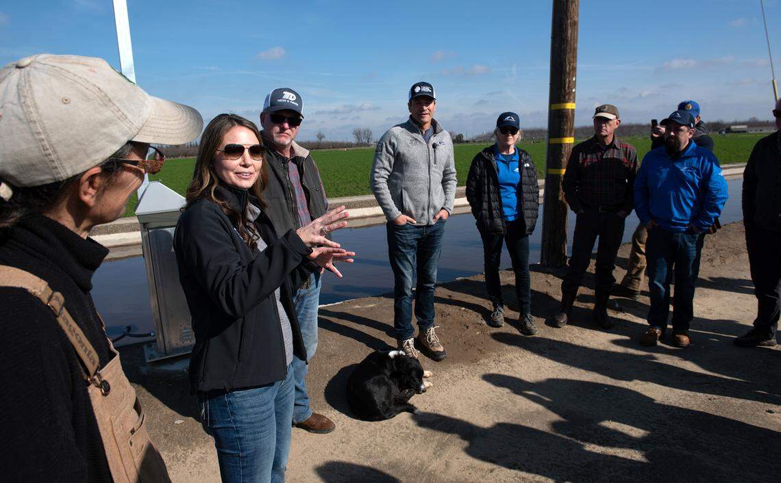 Turlock Irrigation District General Manager Michelle Reimers, left, speaks to state and local officials about its groundwater recharge program along its irrigation canal at the Gemperle family almond orchard near Keyes, Calif., Wednesday, Jan. 18, 2023. TID launched the recharge project in the fall with Sustainable Conservation, a nonprofit based in San Francisco, and the California Department of Water Resources.