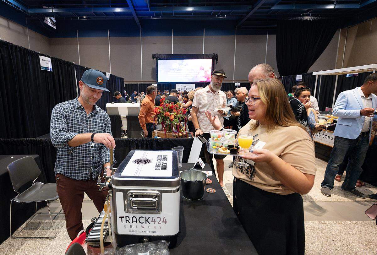 Jon Sciabica from Track 424 brewery pours a beer for Lacey DiFrancia, right, during Edible Extravaganza fundraising event for the Center for Human Services in Modesto, Calif., Thursday, Oct. 5, 2023.