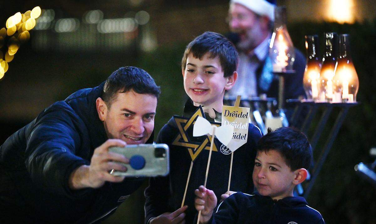 Keith Highiet makes a picture with his two sons Hunter, 8, and Oliver, 4, during the candle lighting ceremony on the third day of Hanukkah outside the Gallo Center for the Arts in Modesto, Calif., Tuesday, Dec. 20, 2022.