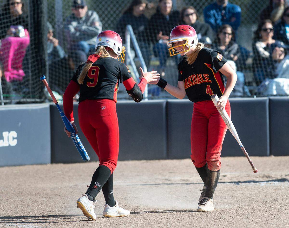 Oakdale’s Delainey Everett (9) greets Avery Brown (4), right, after Brown scored a run during the Valley Oak League game with Central Catholic at Central Catholic High School in Modesto, Calif., on Tuesday, May 10, 2022. Central Catholic won the game 2-1.