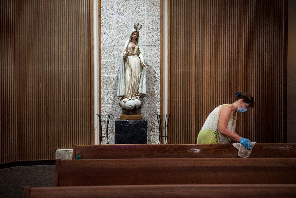 Fatima Medina cleans pews at Sacred Heart Church in Turlock, Calif., on Thursday, May 28, 2020.