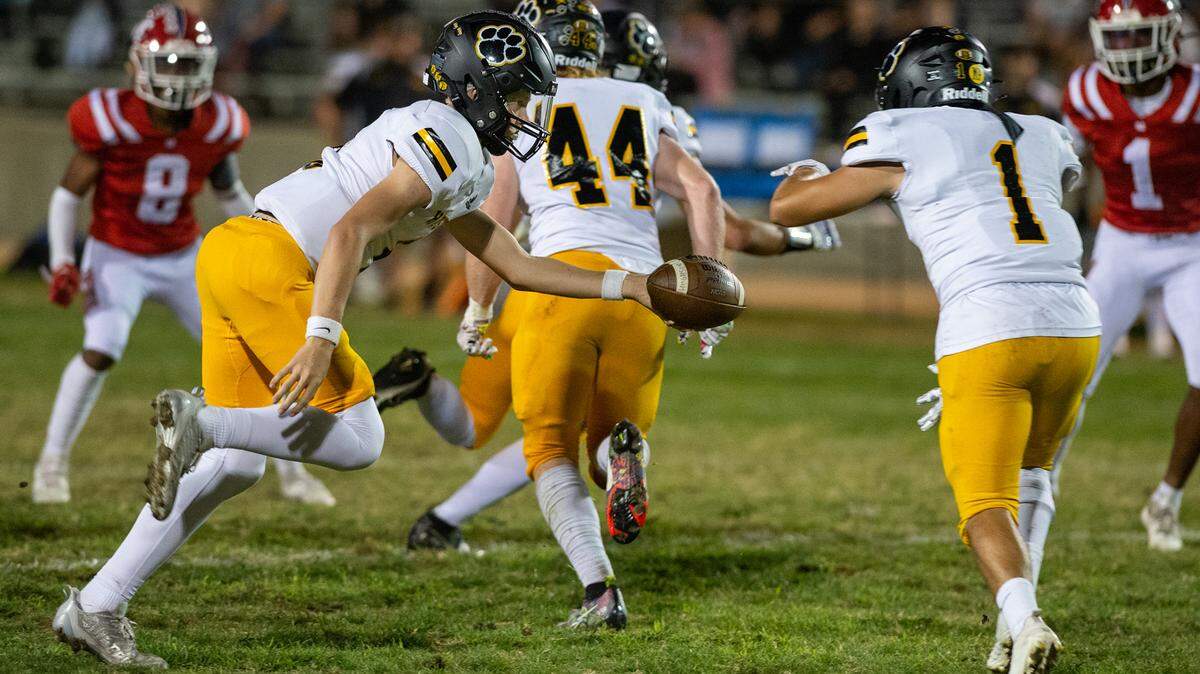 Hughson quarterback Robert McDaniel hands the ball to Alex Villarreal during the Trans Valley League game with Modesto Christian at Modesto Christian High School in Salida, Calif., Thursday, September 29, 2022.