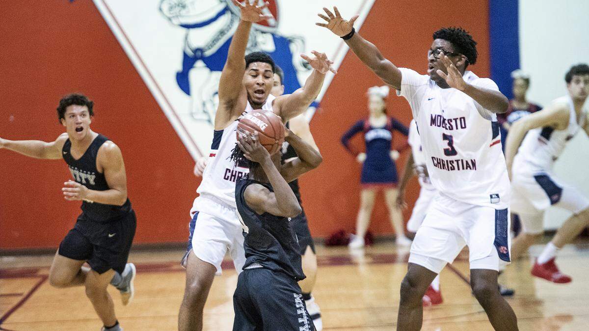 Modesto Christian’s Dathan Satchell, left, and Aaron Murphy, right, pressure Archbishop Mitty’s Marcus Greene during the first round of the CIF State Open Division playoffs at Modesto Christian High School in Salida, Calif., Wednesday, Feb. 27, 2019.