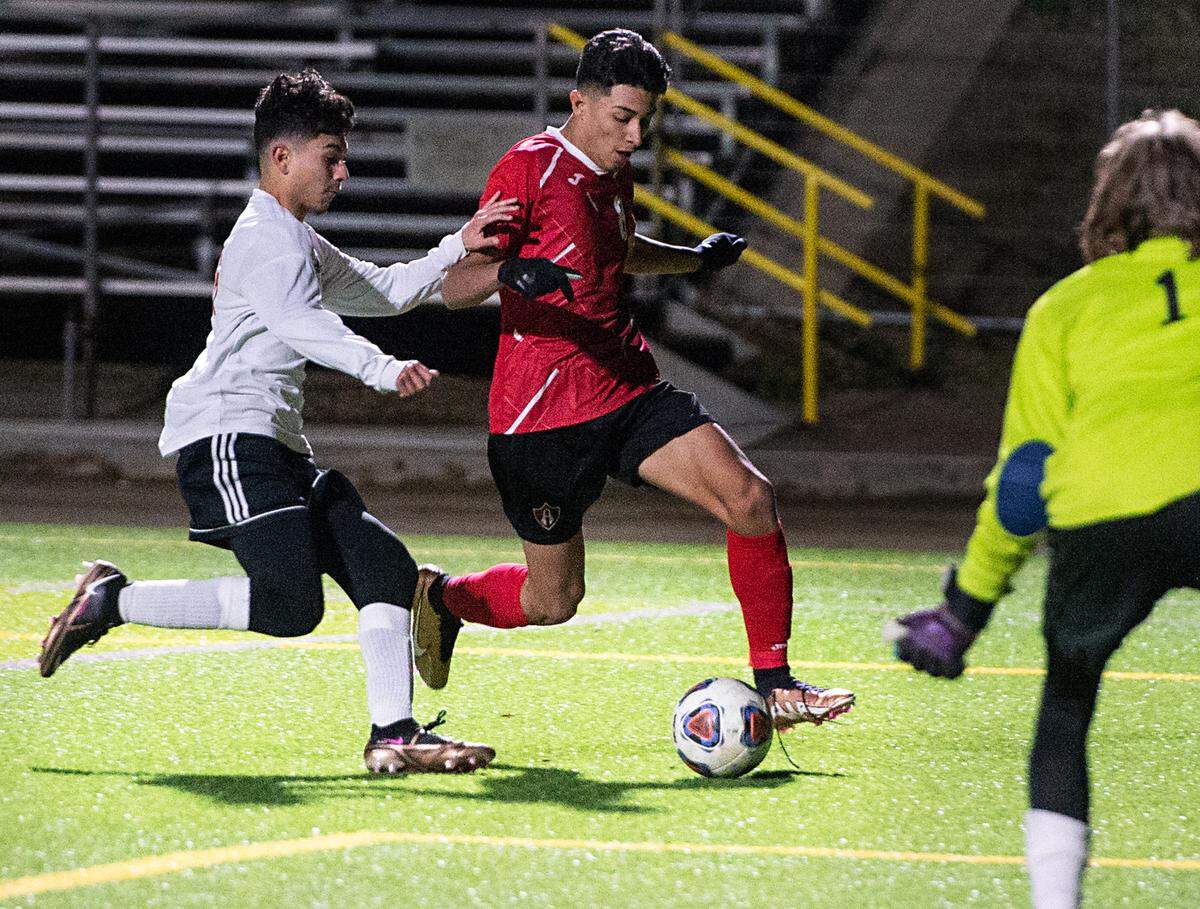 Modesto’s Leonardo Avalos advances the ball past Lincoln’s Luis Ochoa during the first round Division 1 Sac-Joaquin Section Playoff game at Downey High School in Modesto, Calif., Tuesday, Feb. 14, 2023.