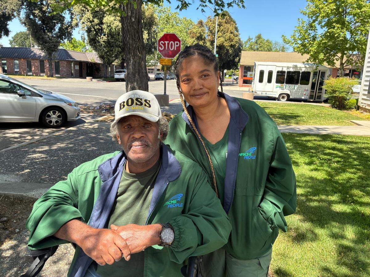 A man in a wheelchair and a women standing outside of Representative McClintock's District Office wearing shorts in support of United Domestic Workers.