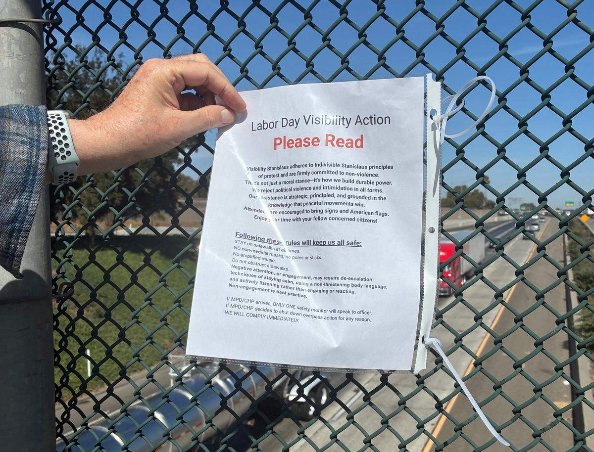 A man hold up a list of principles that Indivisible Stanislaus expects participants to agree to which includes, not wearing a mask for non-medical purposes, staying on the sidewalk but not obstructing it and refraining from loud music.